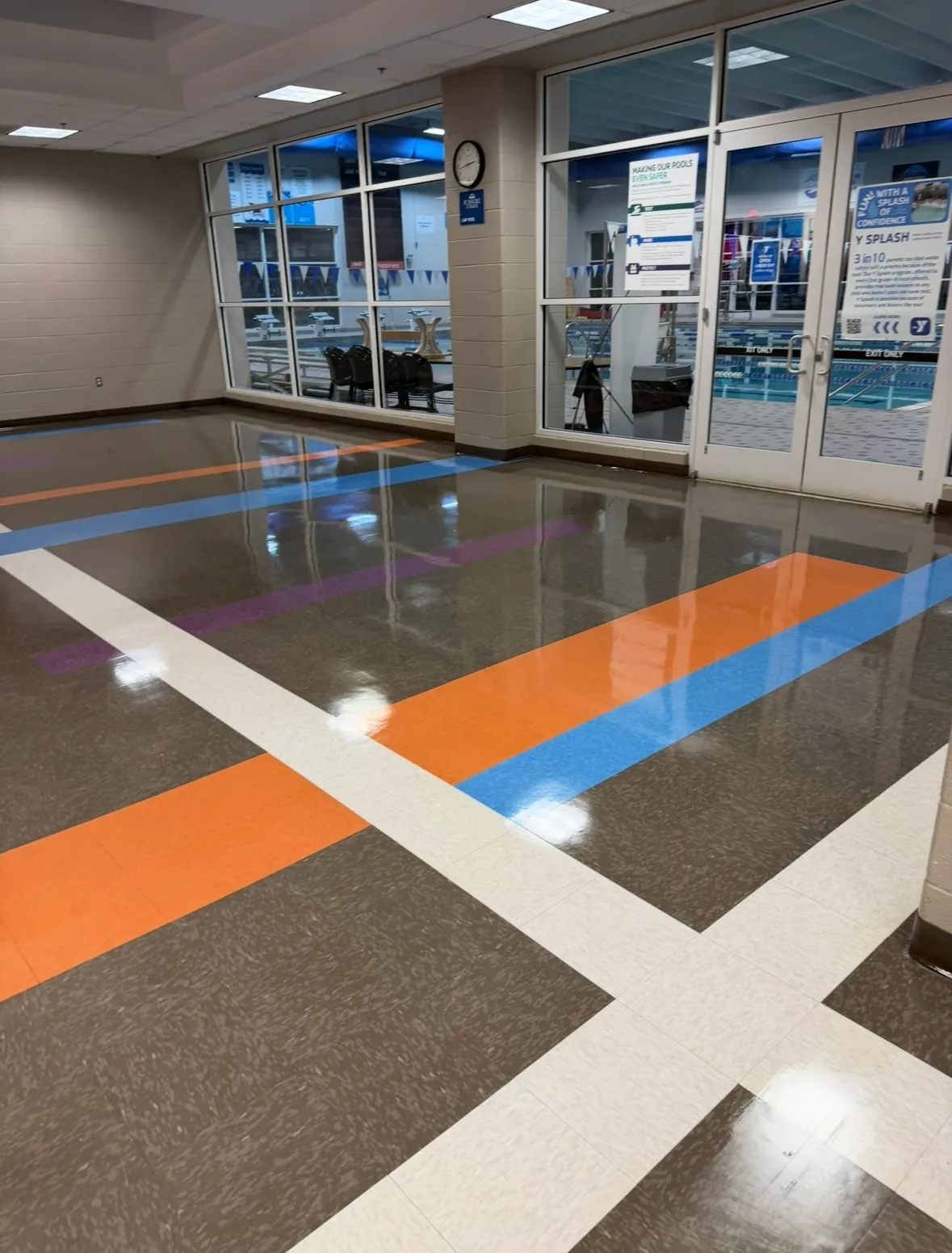 Finished commercial floor with colorful tile bands beside glass entrance doors